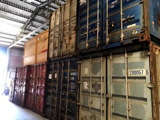 Contenedores marítimos apilados bajo techo en bodega